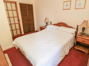 a bedroom with a large white bed and a night stand at Fern Cottage in Wooler