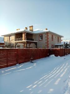 
a house with a snow covered roof and a fence at Эврика! Апартаменты с сауной в частном доме in Velikiy Novgorod
