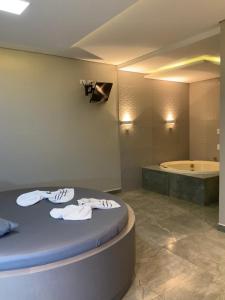 a bathroom with a tub and a bed with towels at Motel Passione in Pinhais