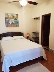 um quarto com uma grande cama branca e uma ventoinha de tecto em Macao Beach em Sámara