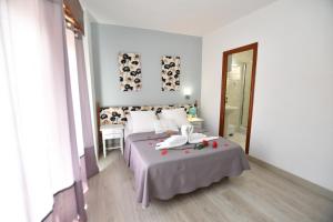 a white bedroom with two beds and a mirror at Hostal HB Torrevieja in Torrevieja