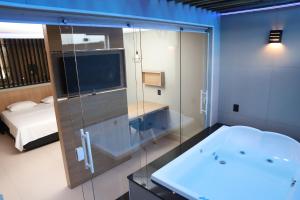 Drops Motel Barretos في باريتوس: حمام مع حوض وغرفة نوم مع سرير