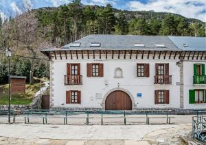 a large white building with a door and a mountain at Albergue de Canfranc Estación in Canfranc-Estación