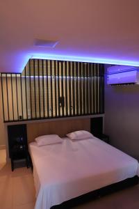 een slaapkamer met een wit bed en paarse verlichting bij Drops Motel Barretos in Barretos