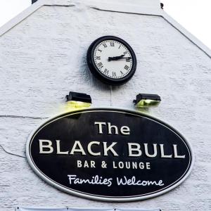 a clock on the side of a bar and lounge sign at The Blackbull Inn Polmont in Polmont