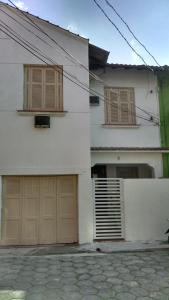 a white house with two garage doors and a building at Pousada Casa 6 in São Vicente