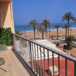 a balcony with a view of a beach and palm trees at Apartamento Torremar in Alicante