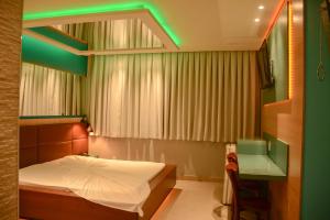 1 dormitorio con 1 cama y luz verde en Motel Sunny Day BH, en Belo Horizonte