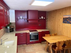 eine Küche mit roten Schränken und einem Holztisch in der Unterkunft Apartmany Na Salasi in Pec pod Sněžkou