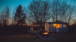 2 personnes assises autour d'un foyer extérieur devant une tente dans l'établissement Shabby Shepherds, à Penrith