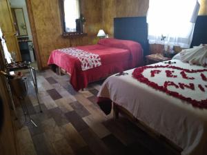 a hotel room with two beds with red sheets at Club Tejamaniles in Los Azufres