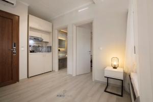 a white hallway with a table and a kitchen at PORTO PORTES suites in Nea Potidaea