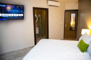 a bedroom with a bed and a tv on the wall at HOTEL ALKQUIMIA in Bayahibe
