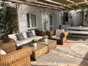 a patio with wicker chairs and a couch and a table at La Casa de la Luz. ArtistHome in Almodóvar del Río
