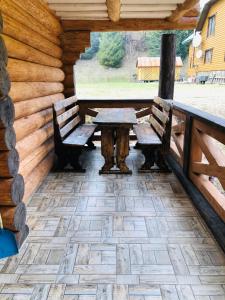 un patio con 2 bancos y una mesa en una cabaña de madera en У ВІТИ котедж4, en Synevyrsʼka Polyana