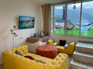 een woonkamer met geel meubilair en een groot raam bij DUBAI by luxury Atitlan in San Pedro La Laguna