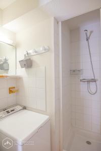 La salle de bains blanche est pourvue d'une douche et d'un lavabo. dans l'établissement Chalets D'Arrondaz, à Valfréjus