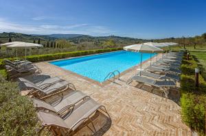 um grupo de cadeiras e guarda-sóis ao lado de uma piscina em Agriturismo Il Segreto di Pietrafitta em San Gimignano