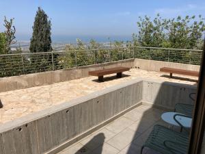 eine Terrasse mit 2 Bänken und Stühlen auf einem Balkon in der Unterkunft Elma Hotel and Art Complex in Zichron Ja’akow