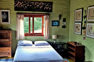 a bedroom with a bed and a window at Pousada Sitio Gan Eden in Visconde De Maua