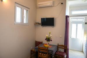 a dining room with a table and a tv on the wall at Aпартаменты Влаович in Igalo
