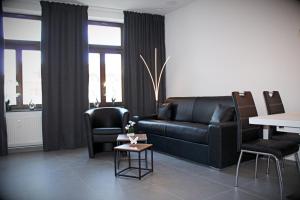 a living room with a black leather couch and chairs at SALZHAUSBLICK FAMILY APARTMENTS - Zentrale Lage am Salzhaus - MwSt-Rechnung verfügbar in Zittau