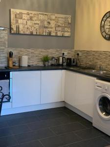 a kitchen with white cabinets and a washer and dryer at Absolute Stays in Sherwood- Nottingham Castle- Capital FM Arena Nottingham- Contractors-Free WIFI- Free Parking- Long and Short Stays- Families-East Midlands Airport-Trent Bridge-Actors-Aria Court- Mansfield in Nottingham