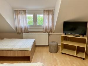 a bedroom with two beds and a flat screen tv at Vincze Vendégház in Körmend