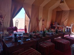 uma longa mesa de madeira numa tenda com cadeiras em Majorelle Desert Camp em Zagora