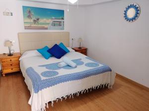 sypialnia z łóżkiem z niebieskimi poduszkami w obiekcie Apartamento Barbacoa, Piscina y playa w mieście Puebla de Farnals
