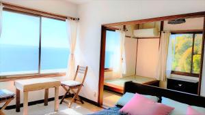 a room with a bed and a table and some windows at AKUA inn in Awaji