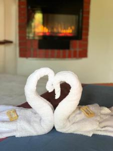 2 toallas con forma de cisne en una cama con chimenea en Hotel Campestre la Loma curiti, en Curití