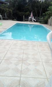 a swimming pool with a tile floor and blue water at Pousada Casa da Vista in Visconde De Maua