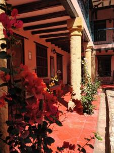 a porch of a house with red flowers in front of it at Hotel Plazuela de San Agustín in Villa de Leyva