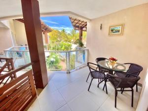 a dining room with a table and chairs on a balcony at Laguna Ville in Itacimirim