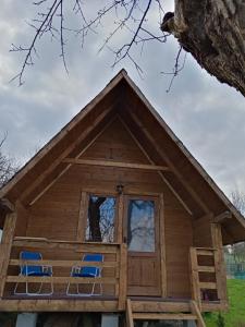 2 sillas en el porche de una cabaña de madera en Cabana Ema, en Beclean