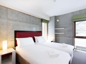 dwa łóżka w pokoju ze ścianą w obiekcie Kita Kitsune Chalet w mieście Niseko