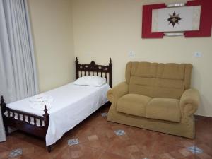 a bedroom with a bed and a couch and a chair at POUSADA FAROL DE ALEXANDRIA LTD - ME in Cândido Mota