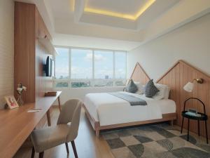 ein Schlafzimmer mit einem großen Bett, einem Schreibtisch und einem großen Fenster in der Unterkunft Fika Rooms Tangerang By Skandinavia in Tangerang