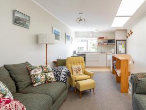 a living room with a couch and a chair and a kitchen at Beachside at Snells - Snells Beach Apartment in Snells Beach