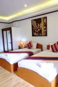 2 Betten in einem Zimmer mit weißen Wänden in der Unterkunft WeRest Hotel in Khon Kaen