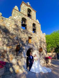 une mariée et un marié se tenant devant un bâtiment en pierre dans l'établissement Hacienda de los Santos, à Álamos