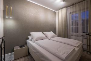 um quarto com uma cama com lençóis brancos e uma janela em Na Skałce Apartment em Cracóvia