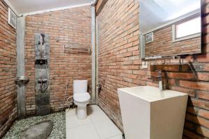 a brick bathroom with a toilet and a sink at Balkondes Kenalan in Magelang