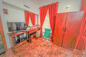 a room with a desk and a television and red curtains at Y&Y Residence in Kandy
