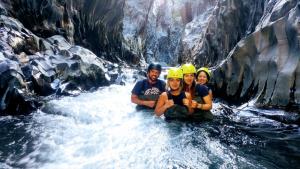 un grupo de tres personas sentadas en un río en Gole Alcantara mini Campeggio privato, en Motta Camastra