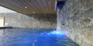 uma piscina com luzes azuis numa parede de pedra em L Ame et Son du Coeur em Dorénaz