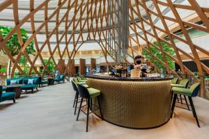 a bar in a restaurant with chairs and a person at PARKROYAL COLLECTION Marina Bay, Singapore in Singapore