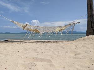 a hammock on a beach next to the water at Sea Love Beach Bar & Bungalows in Ban Tai