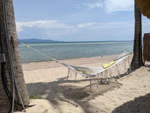 a hammock hanging from two palm trees on a beach at Sea Love Beach Bar & Bungalows in Ban Tai